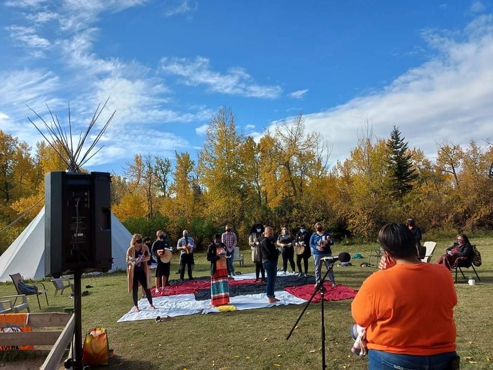 A group of individuals gather outdoors during fall to participate in a blanket exercise.