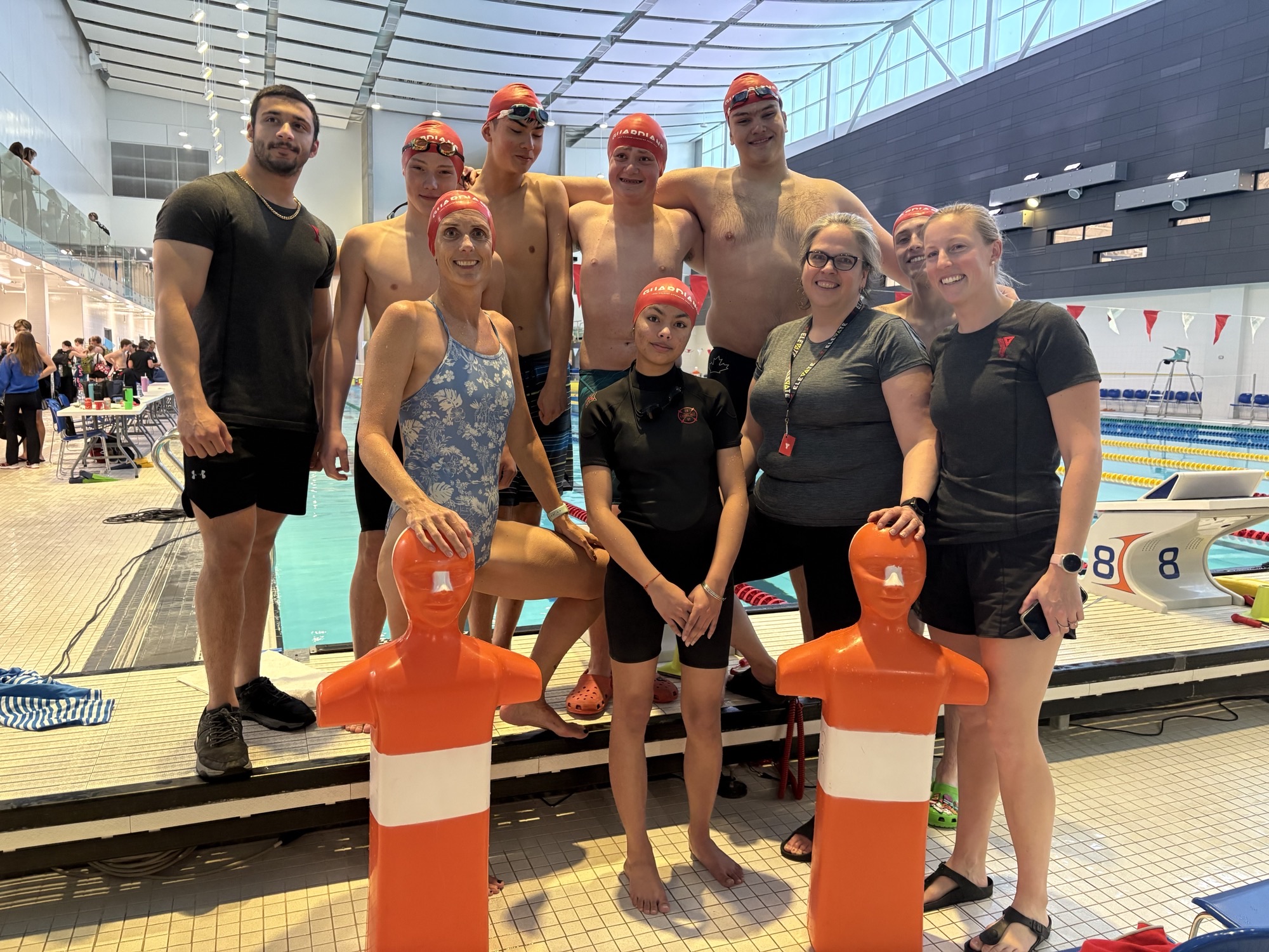 A group of swimmers pose next to a pool