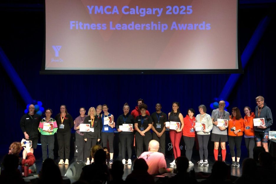 Group of people standing on stage with awards