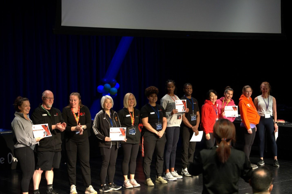 Group of people standing on stage with awards