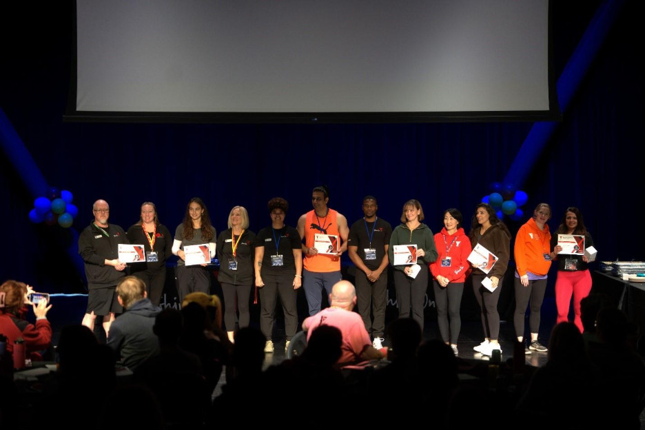 Group of people standing on stage with awards