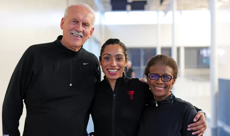 A group of three individuals stand next to each other, donning smiles and YMCA clothing