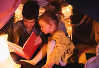 Kids reading a book underneath a fort