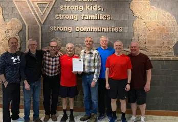 A group of eight older adults standing together smiling