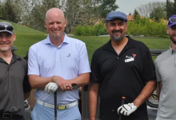 Four men standing with golf clubs 