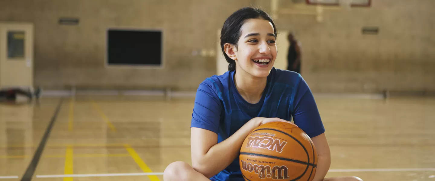 girl sitting in gymnasium with basketball