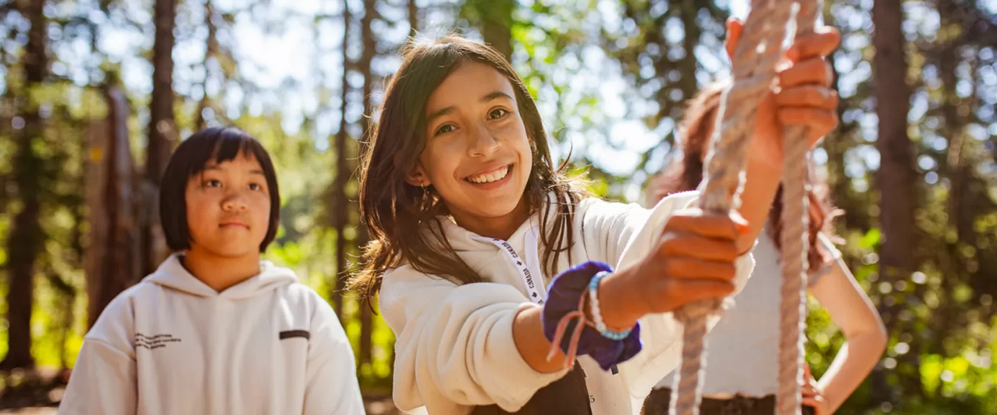 A young girl smiles while trying out the challenge course