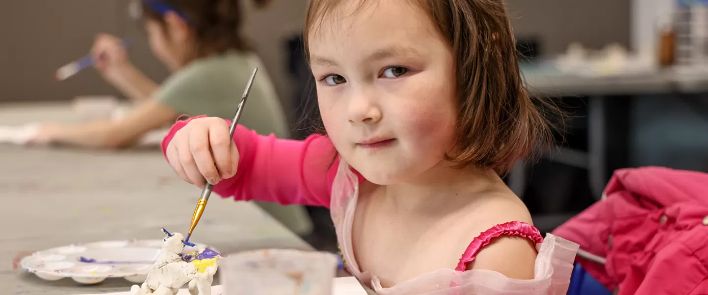 A child poses for a photo while painting