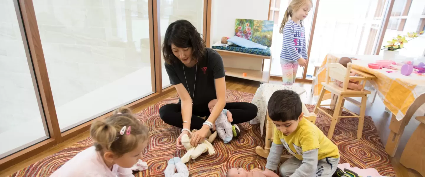 YMCA staff playing dolls with children