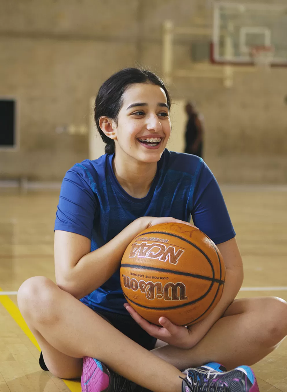girl sitting in gymnasium with basketball