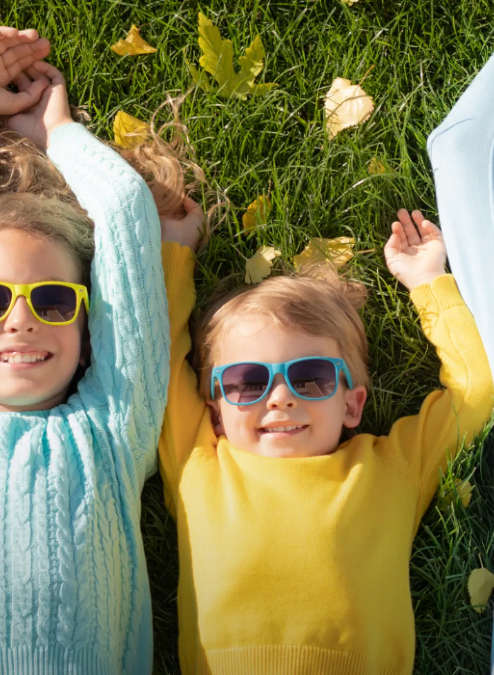 A family lays in the summery grass with matching sunglasses and smiles