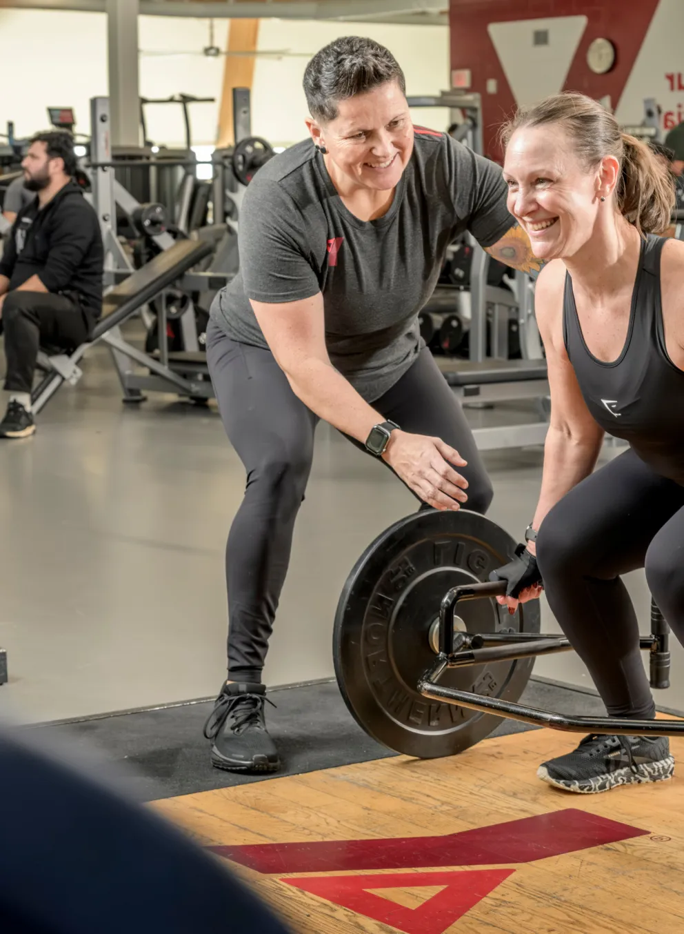 YMCA trainer helping a happy woman weightlifting