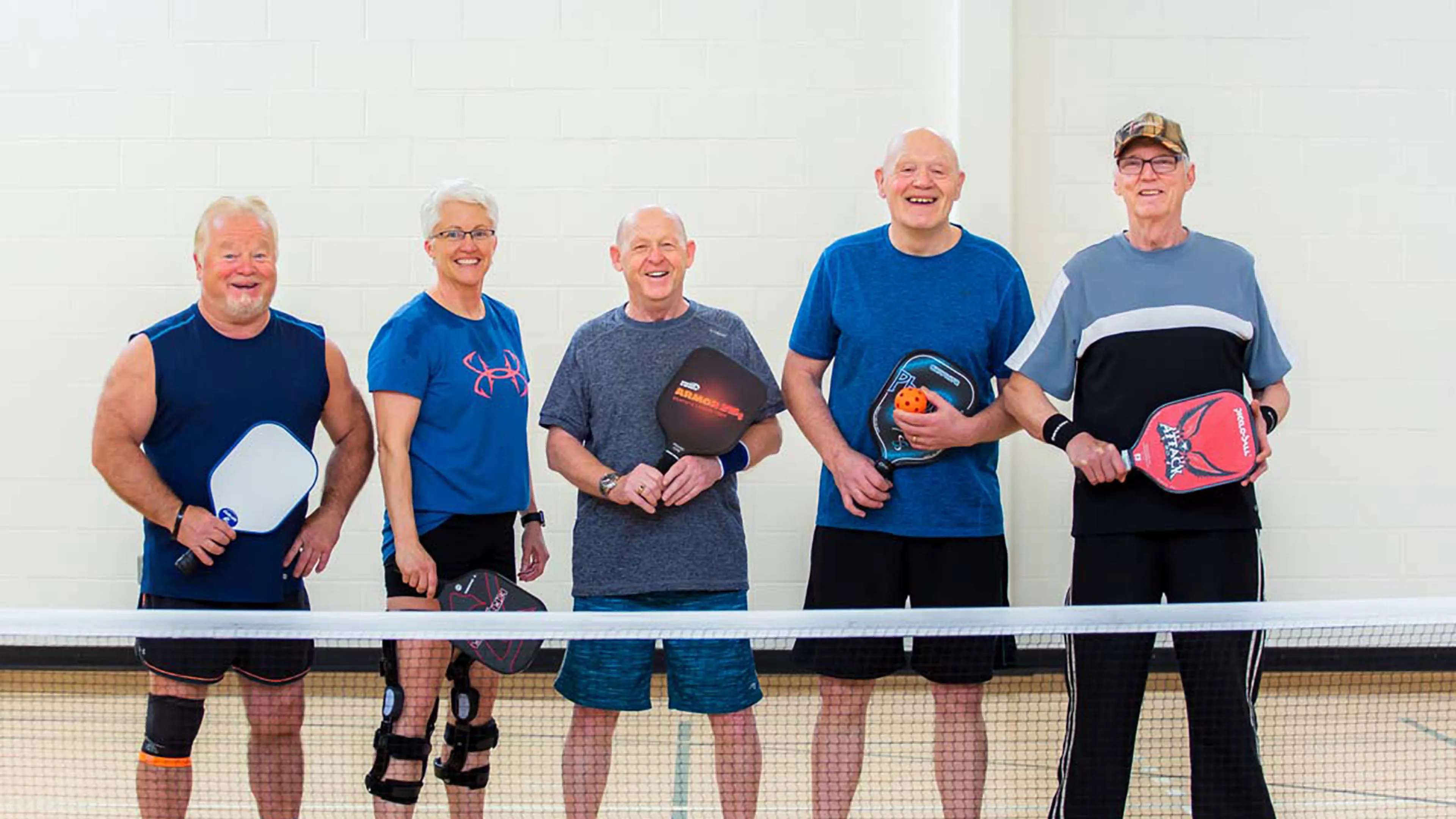 group of older men play pickle ball