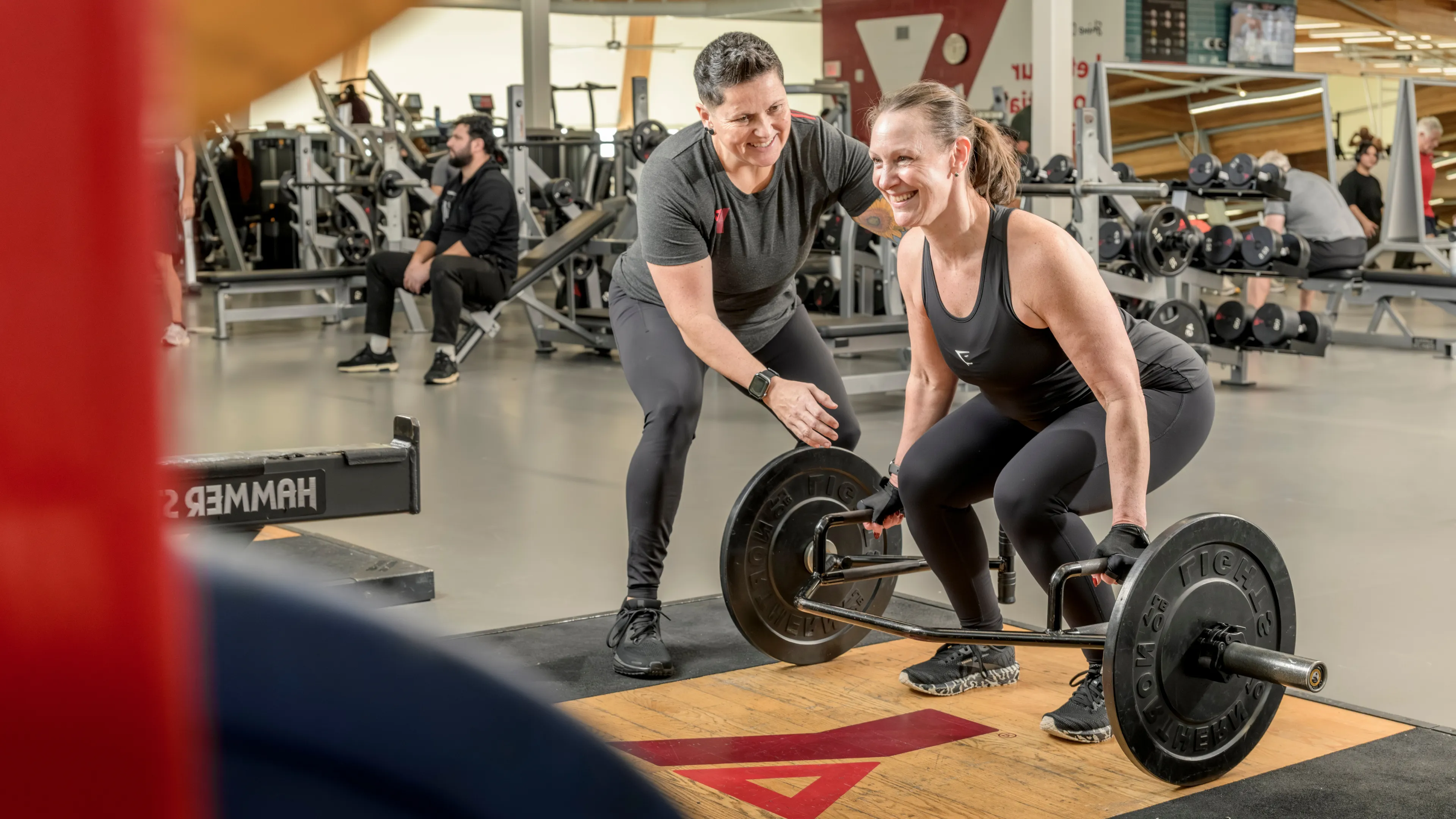 YMCA trainer helping a happy woman weightlifting
