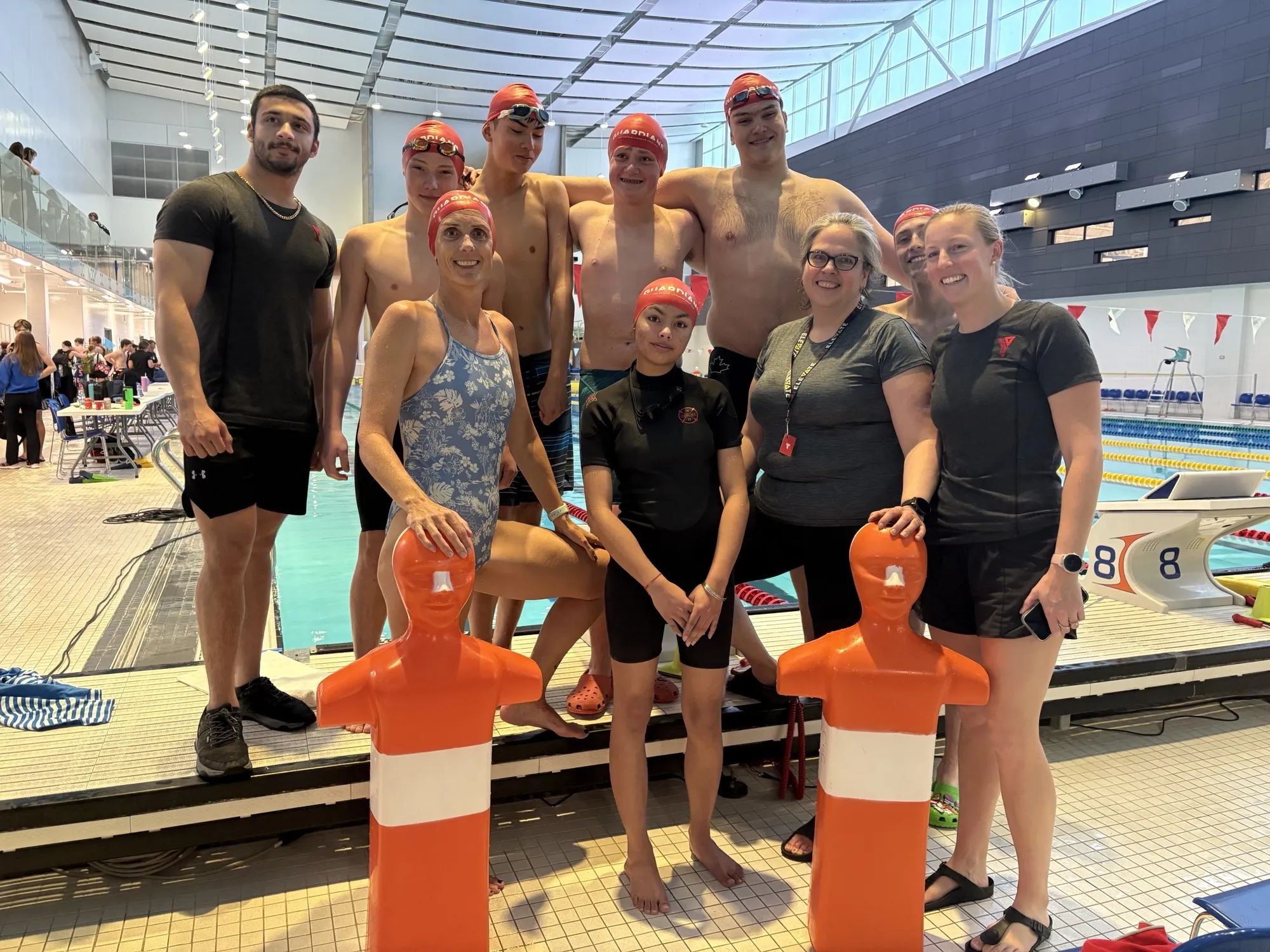 A group of swimmers pose next to a pool