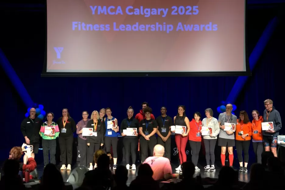 Group of people standing on stage with awards