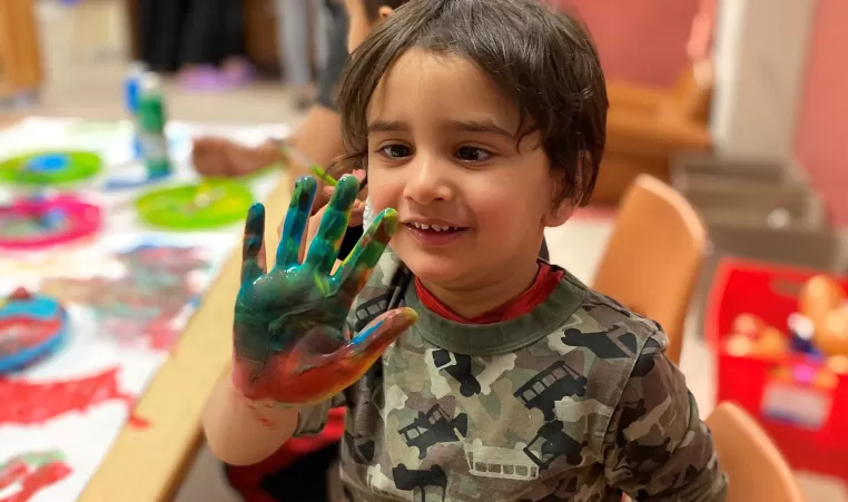 Little boy shows his hand covered in paint