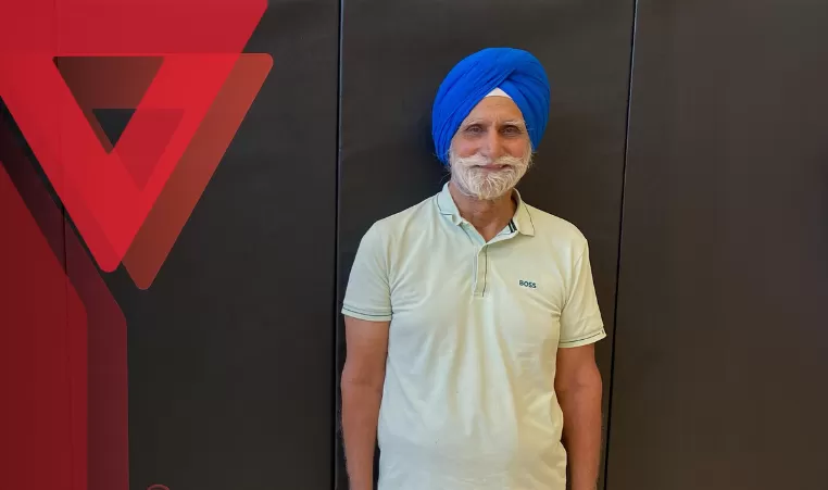 Mukinderpal Uppal smiles in front of a black gym mat background