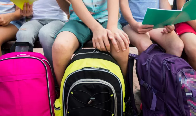 Kids sit with backpacks