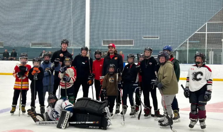 Group of kids with Calgary Flames player, Ryan Lomberg, on the ice