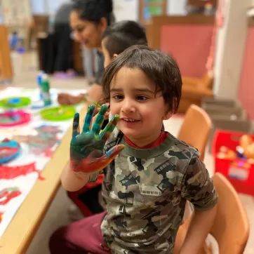 Little boy shows his hand covered in paint