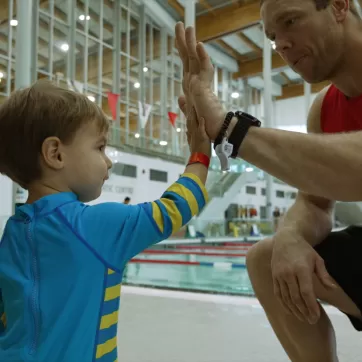 A YMCA Calgary lifeguard high-fives a young swimmer