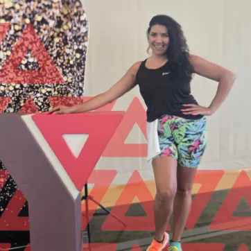 Aphrodit standing next to the YMCA symbol