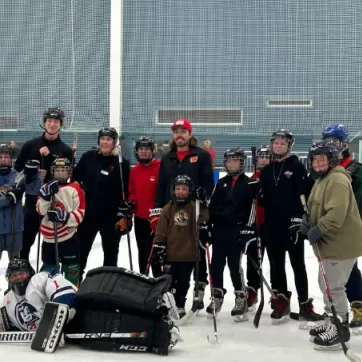 Group of kids with Calgary Flames player, Ryan Lomberg, on the ice