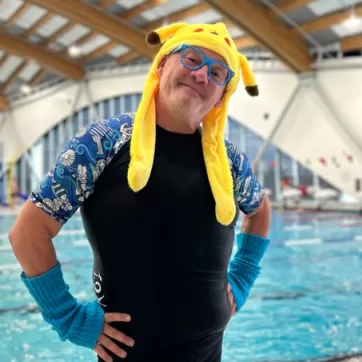 Man with glasses wearing a pikachu hat in front of a pool