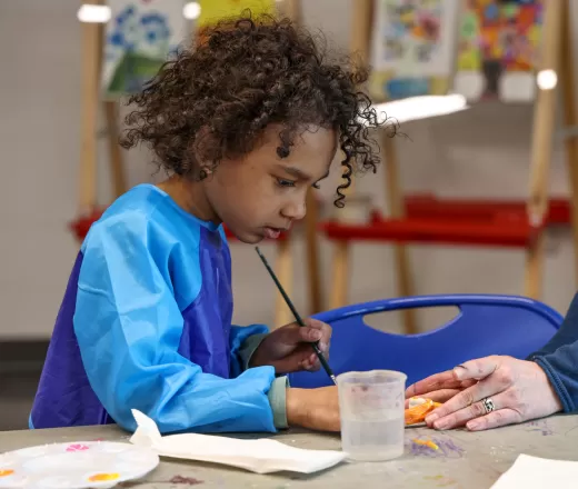 A young child paints in an art class