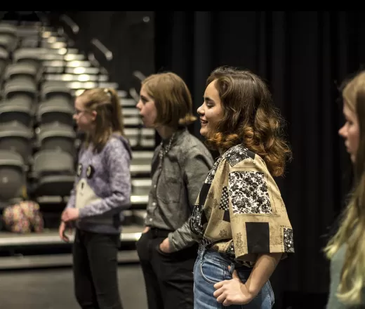 A group of youth stand together in a theatre
