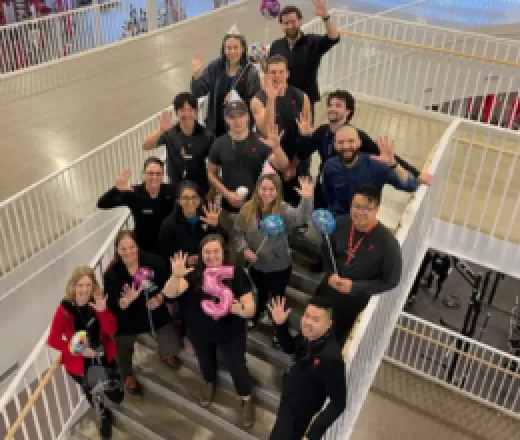 group of people standing on stairs holding up hands to show the number 5
