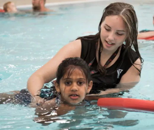 Girl helping other girl with swimming