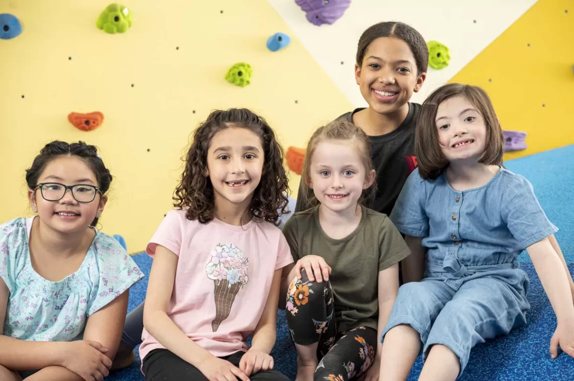 staff with children in front of climbing wall
