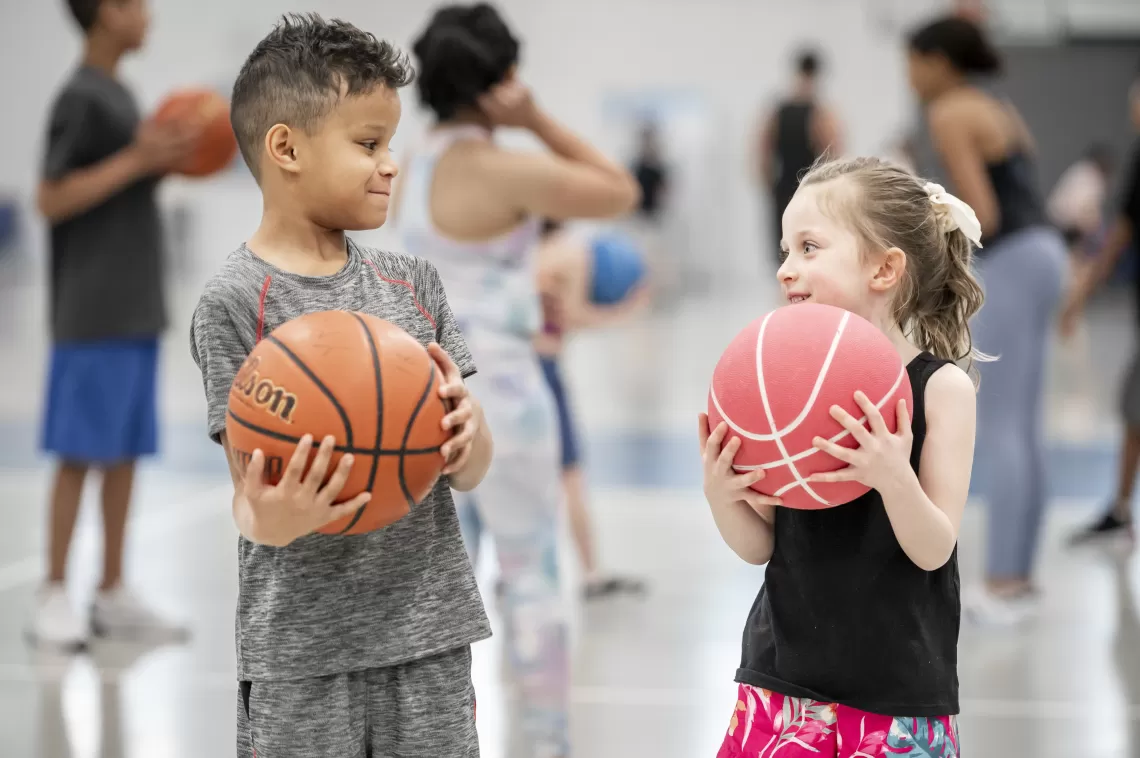 two kids holding basketballs facing each other