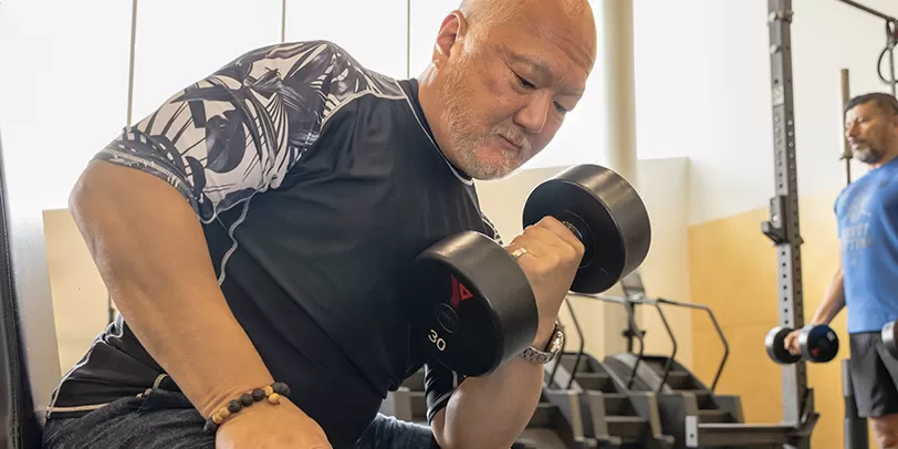 Senior lifting a dumbbell at YMCA Calgary Gym Weight floor