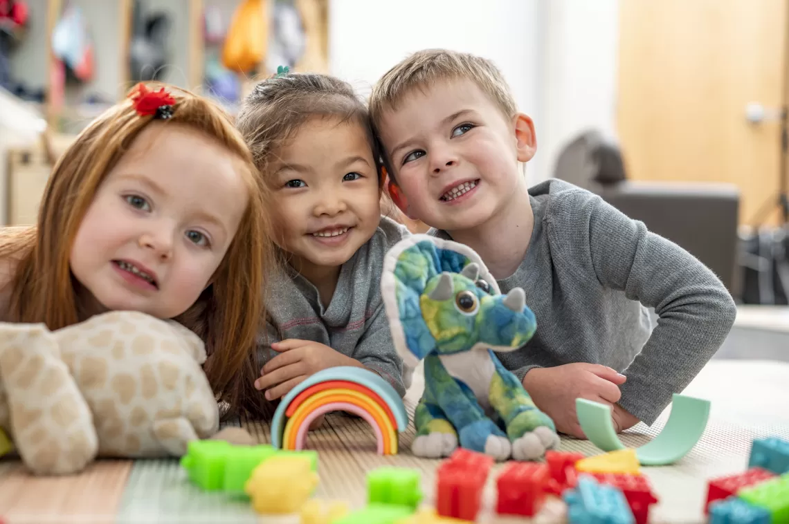 Three kids smiling and playing with toys together