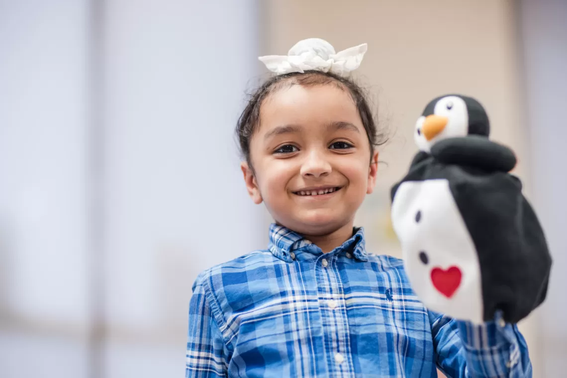 Girl holding a penguin hand puppet