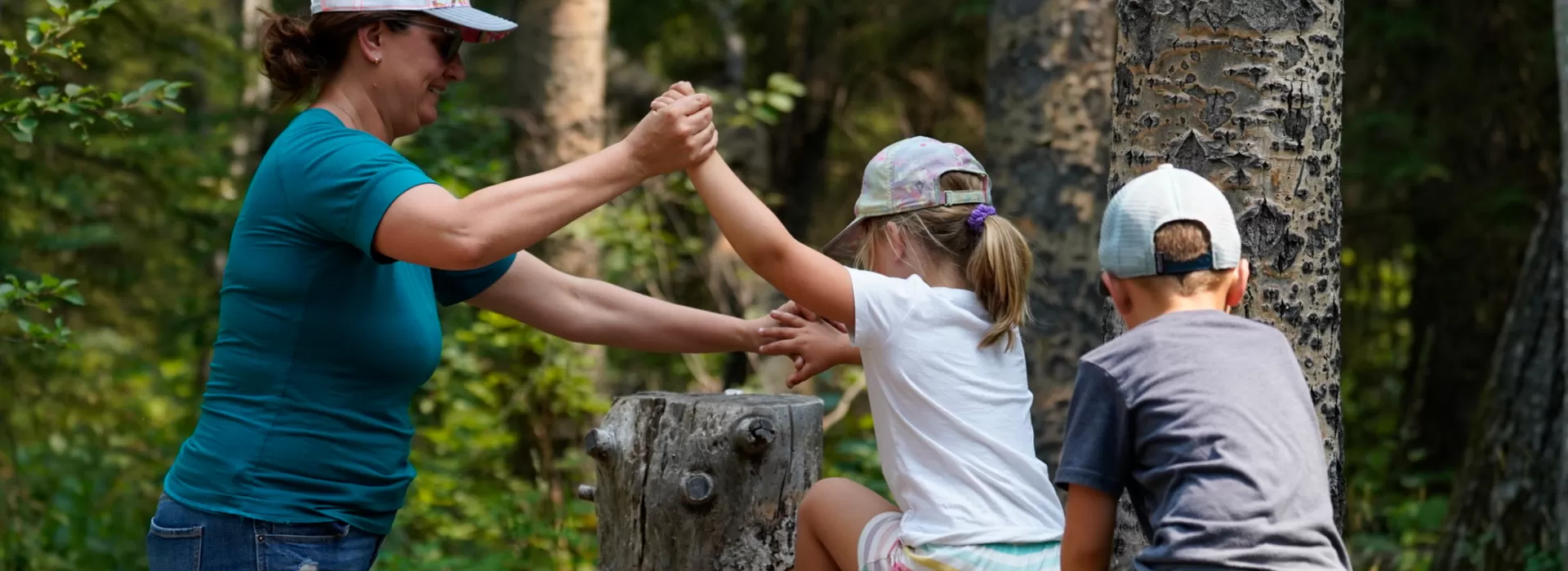 Mom helping kids on logs