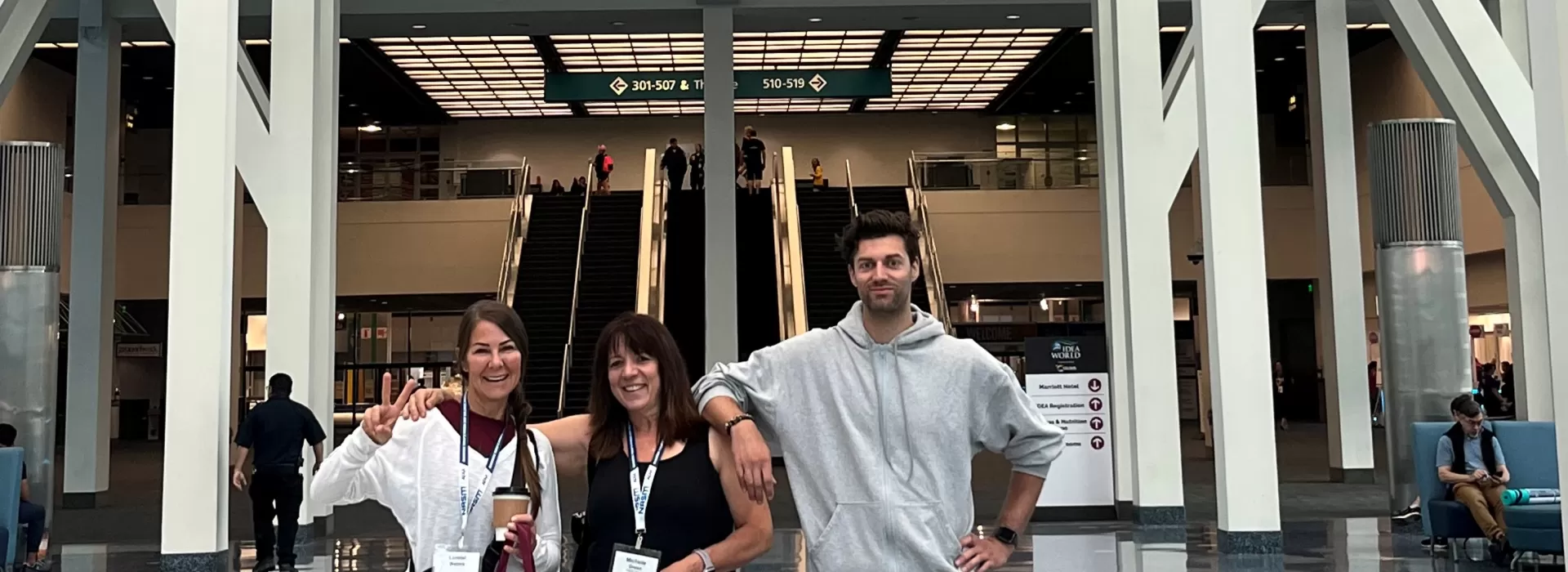 three people standing in front of a welcome sign at a conference