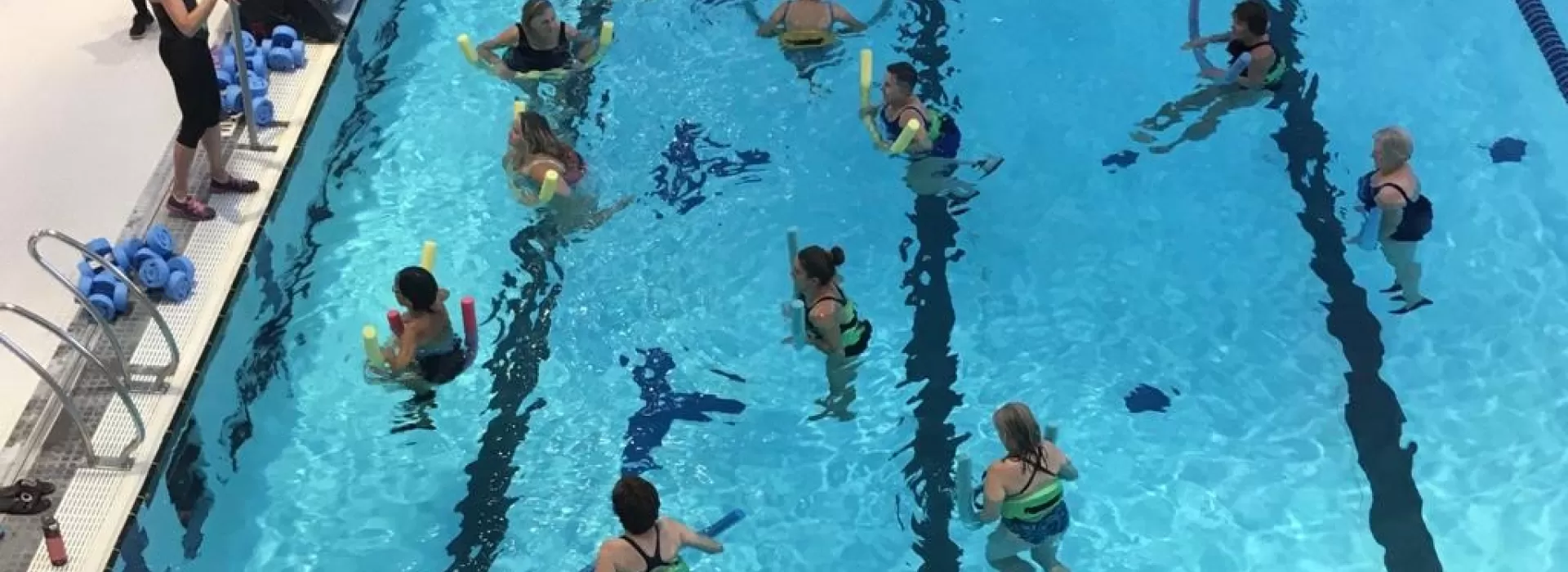 group of people listening to an instructor in a pool