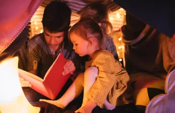 Kids reading a book underneath a fort