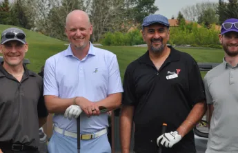 Four men standing with golf clubs 