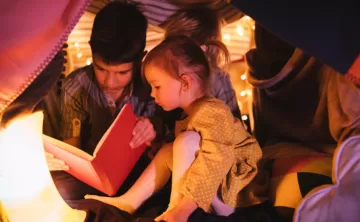 Kids reading a book underneath a fort