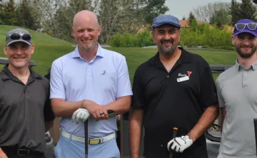 Four men standing with golf clubs 